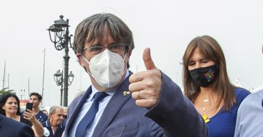 Catalan separatist leader Carles Puigdemont (L) gives thumbs up as he walks with the Speaker of the Catalan Parliament Laura Borras in Alghero, Sardinia, Italy, Saturday, Sept. 25, 2021. (AP Photo)