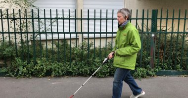 Laurence Jamet, Parisian woman blind since birth, walks with a cane and the electronic device, called Rango, invented by the Lyon-based startup Gosense, which uses sound and augmented reality to warn visually impaired people before a collision can occur, during an interview with Reuters in Paris, France, Sept. 21, 2021. (REUTERS Photo)