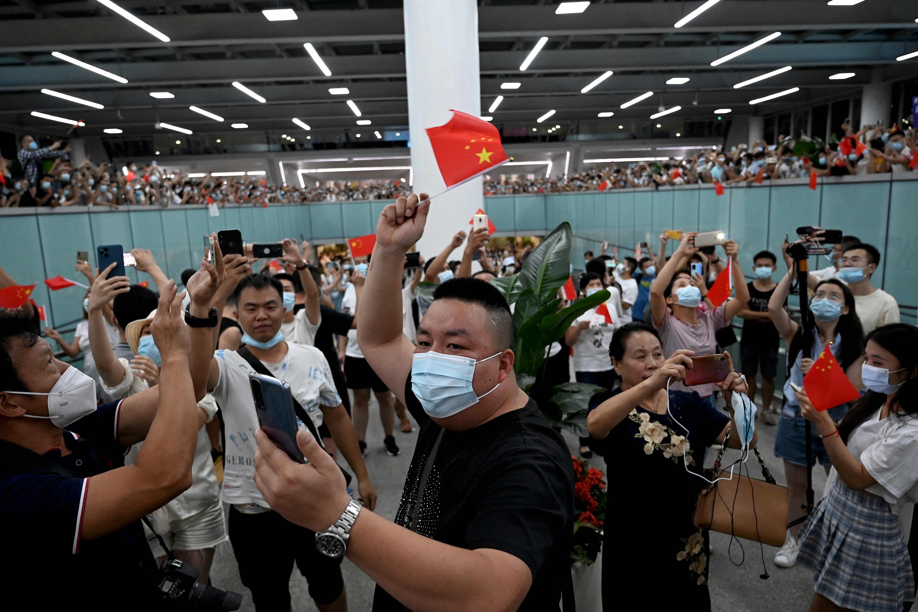 Supporters wave Chinese national flags as they wait for the arrival of Huawei CFO Meng Wanzhou at the Shenzhen Baoan International Airport in Shenzhen, Guangdong Province, China, Sept. 25, 2021. (AFP Photo)