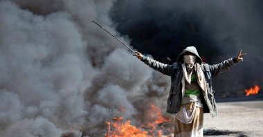 A Yemeni man flashes the V for victory sign next to burning tires during protests calling for the removal of the Saudi-backed coalition government and deteriorating economic and living conditions, in Yemen's third city of Taez on Sept. 27, 2021. (AFP Photo)