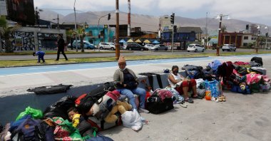 Venezuelan migrants sit along a street next to the ocean after their camp was destroyed during violent anti-immigration protests, in Iquique, Chile, September 27, 2021. (Reuters Photo)
