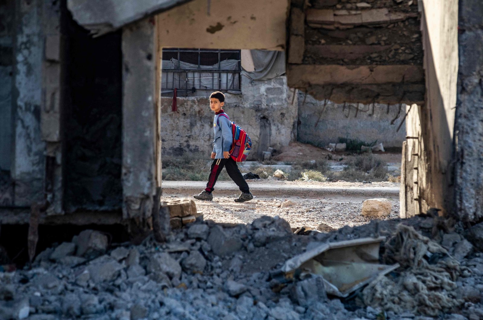 A Syrian student walks to school past damaged buildings in the northern city of Raqqa, Syria, Sept. 23, 2021. (AFP Photo)