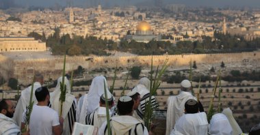 Orthodox Jews wearing prayer shawls and carrying the "four species" (the four plants that are mentioned in the Torah as being relevant to Sukkot) pray during a special prayer called "Hoshana Raba" as part of the celebration of the seventh day of Sukkot, the Feast of the Tabernacles, in the Mount of Olives with a view of the Old City of Jerusalem, Israel, Sept. 27, 2021. (EPA Photo)