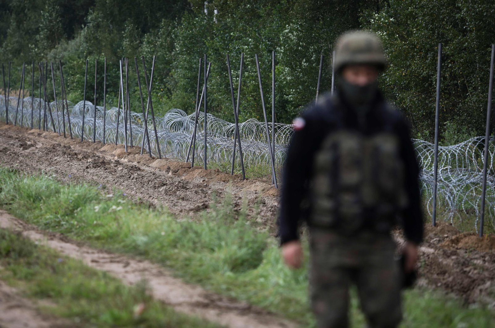 A Polish soldier walks past a barbed wire fence under construction on the border with Belarus in Zubrzyca Wielka near Bialystok, eastern Poland, Aug. 26, 2021. (AFP Photo)