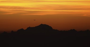 A plane flies above Mont-Blanc as the sun rises over France, Sept. 27, 2021. (AP Photo)