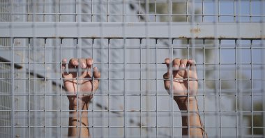In this Sept. 30, 2016, file photo, a migrant from Afghanistan holds onto a fence after crossing to Hungary from Serbia in Roszke, Hungary. (AP Photo)