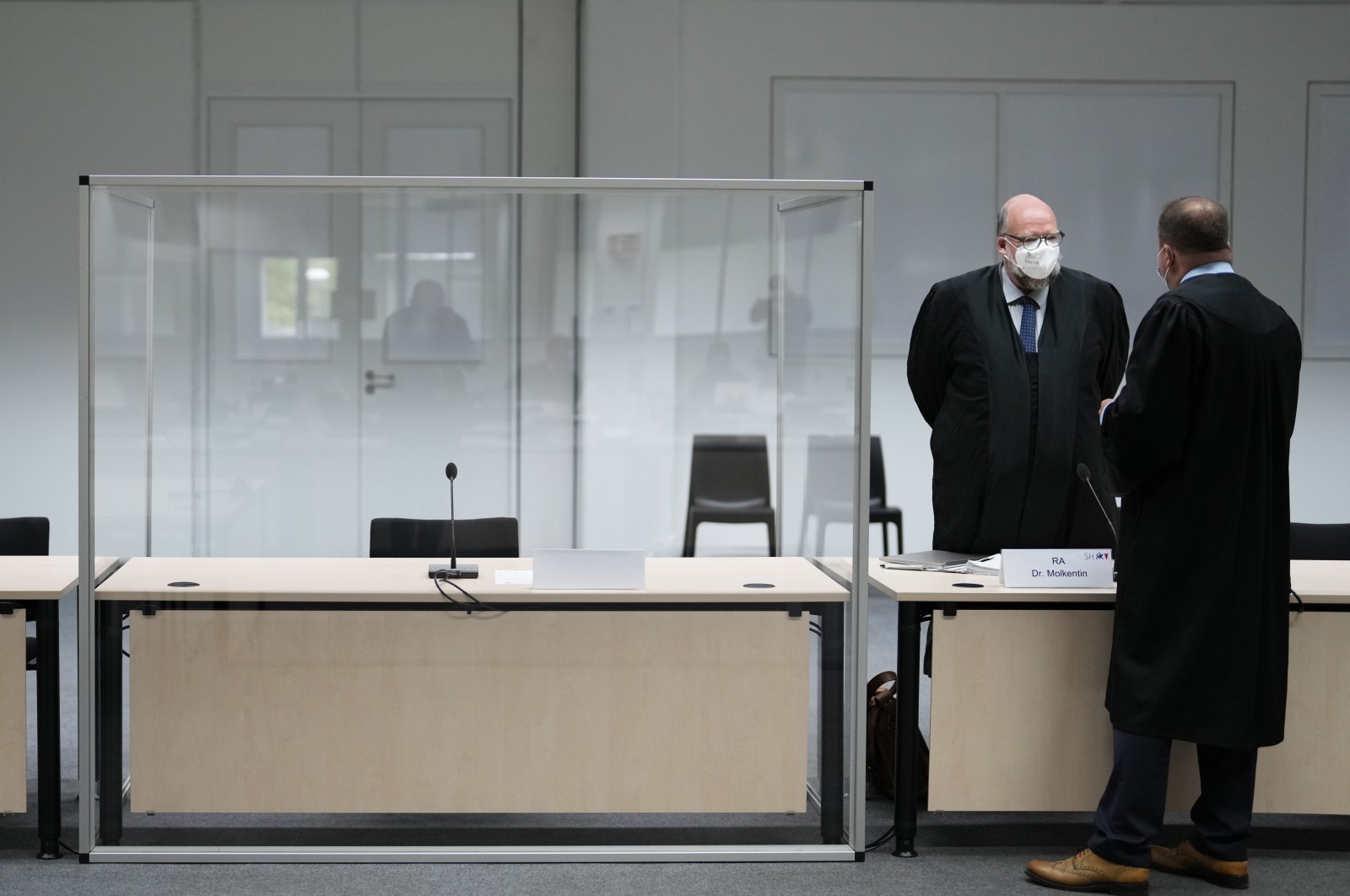 Two people stand next to an empty seat of the accused at the courtroom, prior to a trial against a 96-year-old former secretary for the SS commander of the Stutthof concentration camp at the court in Itzehoe, Germany, Sept. 30, 2021. (AP Photo)