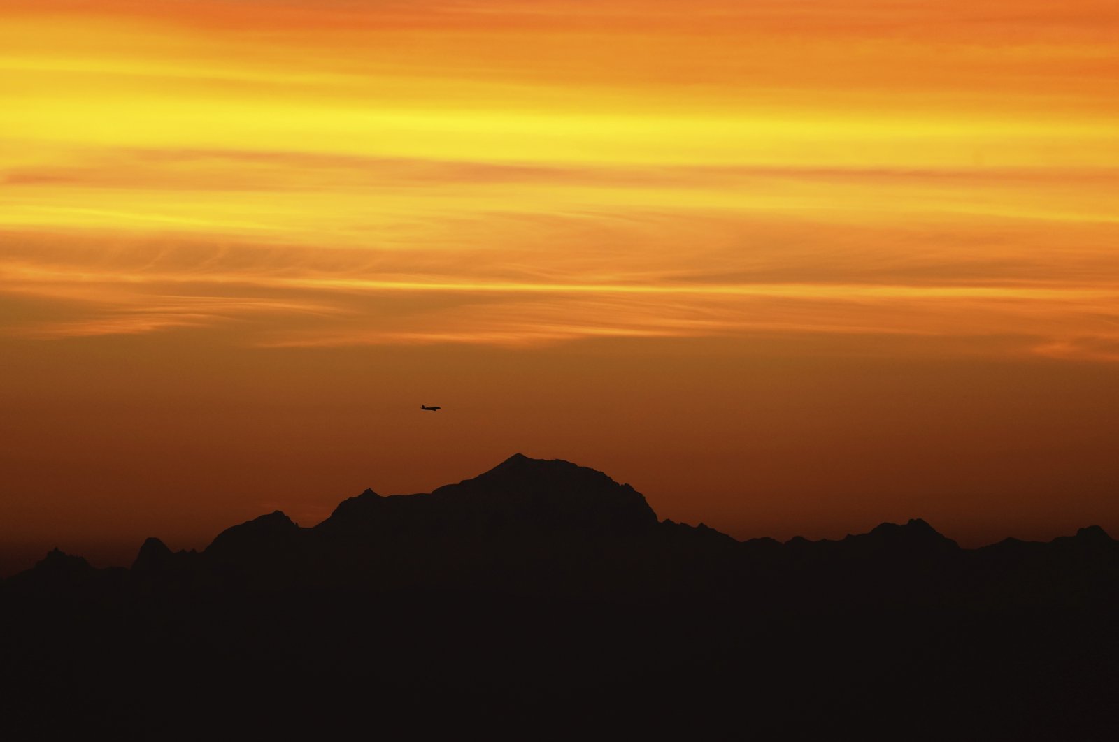 A plane flies above Mont-Blanc as the sun rises over France, Sept. 27, 2021. (AP Photo)