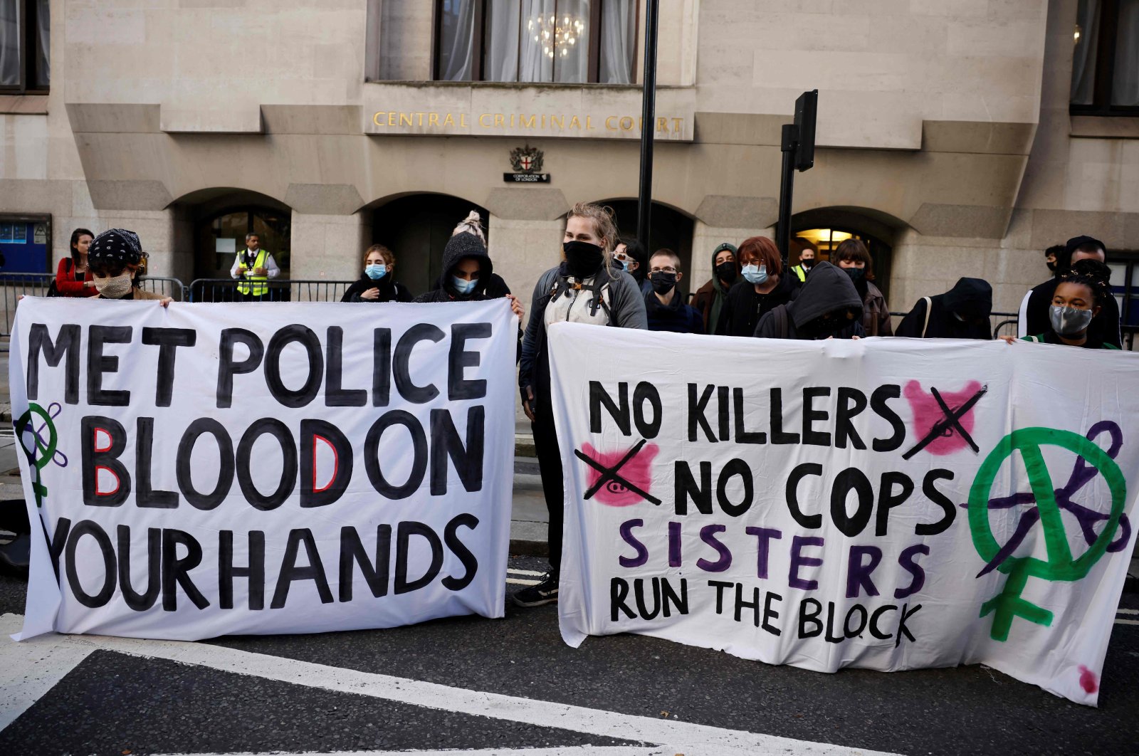 Demonstrators hold banners as they await the sentencing of British police officer Wayne Couzens for the murder of Sarah Everard, outside the Old Bailey court in London on Sept. 29, 2021. (AFP Photo)