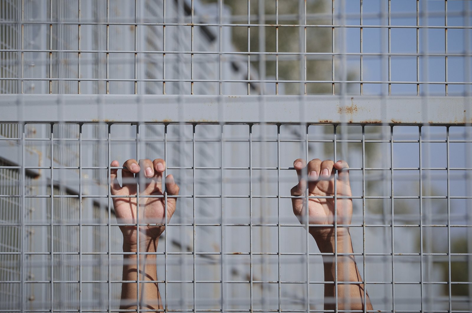 In this Sept. 30, 2016, file photo, a migrant from Afghanistan holds onto a fence after crossing to Hungary from Serbia in Roszke, Hungary. (AP Photo)