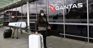 Travelers arrive at a deserted Qantas terminal at Melbourne Airport, Melbourne, Australia, Aug. 26, 2021. (AFP Photo)