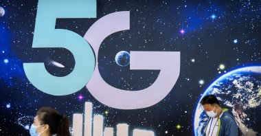 Attendees walk past a booth advertising 5G telecommunications services at the PT Expo in Beijing, China, Sept. 28, 2021. (AP Photo)
