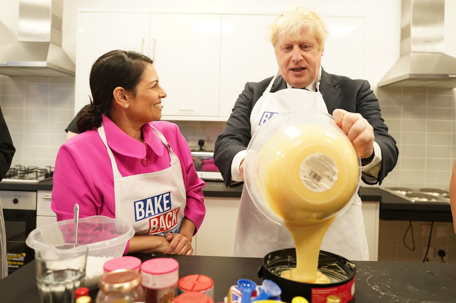 Britain's Prime Minister Boris Johnson and Home Secretary Priti Patel try baking during a visit to HideOut Youth Zone, in Manchester, England, Oct. 3, 2021. (AP Photo)