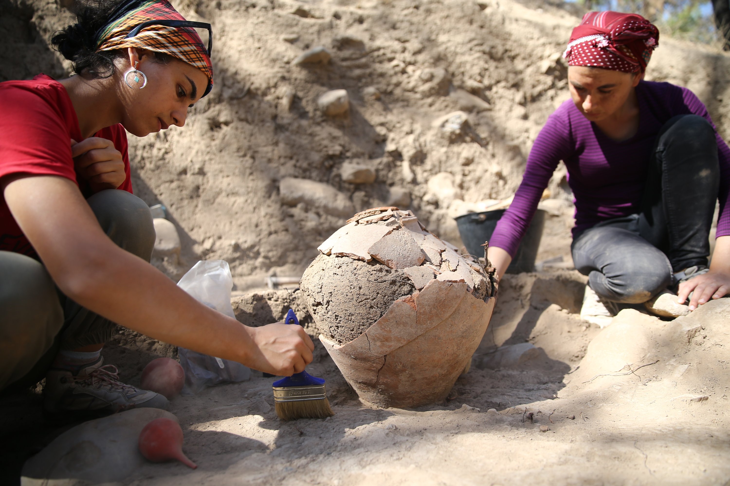 Archaeologists work on the 4,500-year-old jar in the Yumuktepe Mound, Mersin, southern Turkey, Oct. 3, 2021. (AA Photo) 