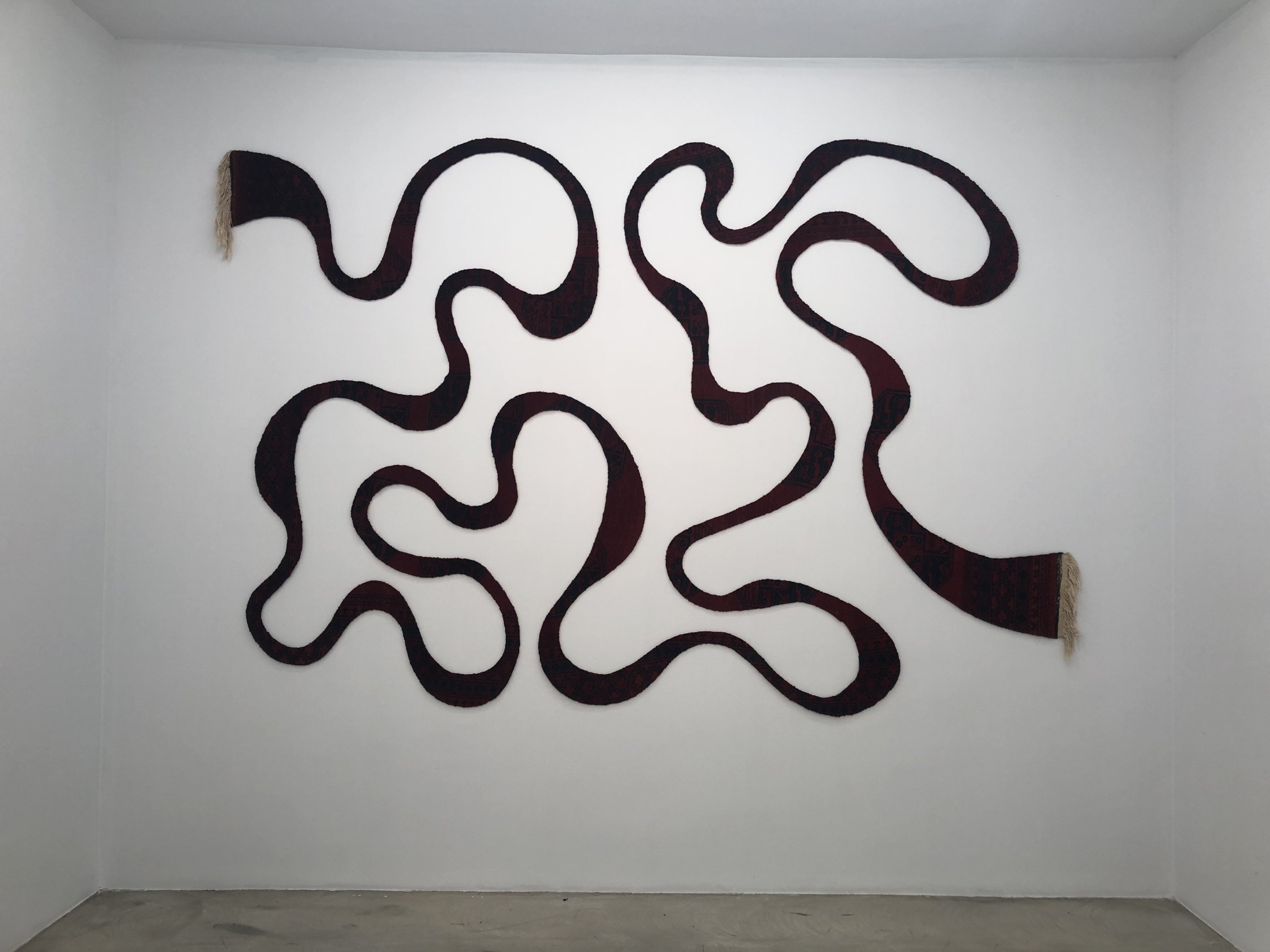 The snaking tendrils of one carpet, carved into a single squiggle by Şakir Gökçebağ in 'Redimeyd' at Ferda Art Platform in Istanbul, Turkey. (Courtesy of Şakir Gökçebağ)