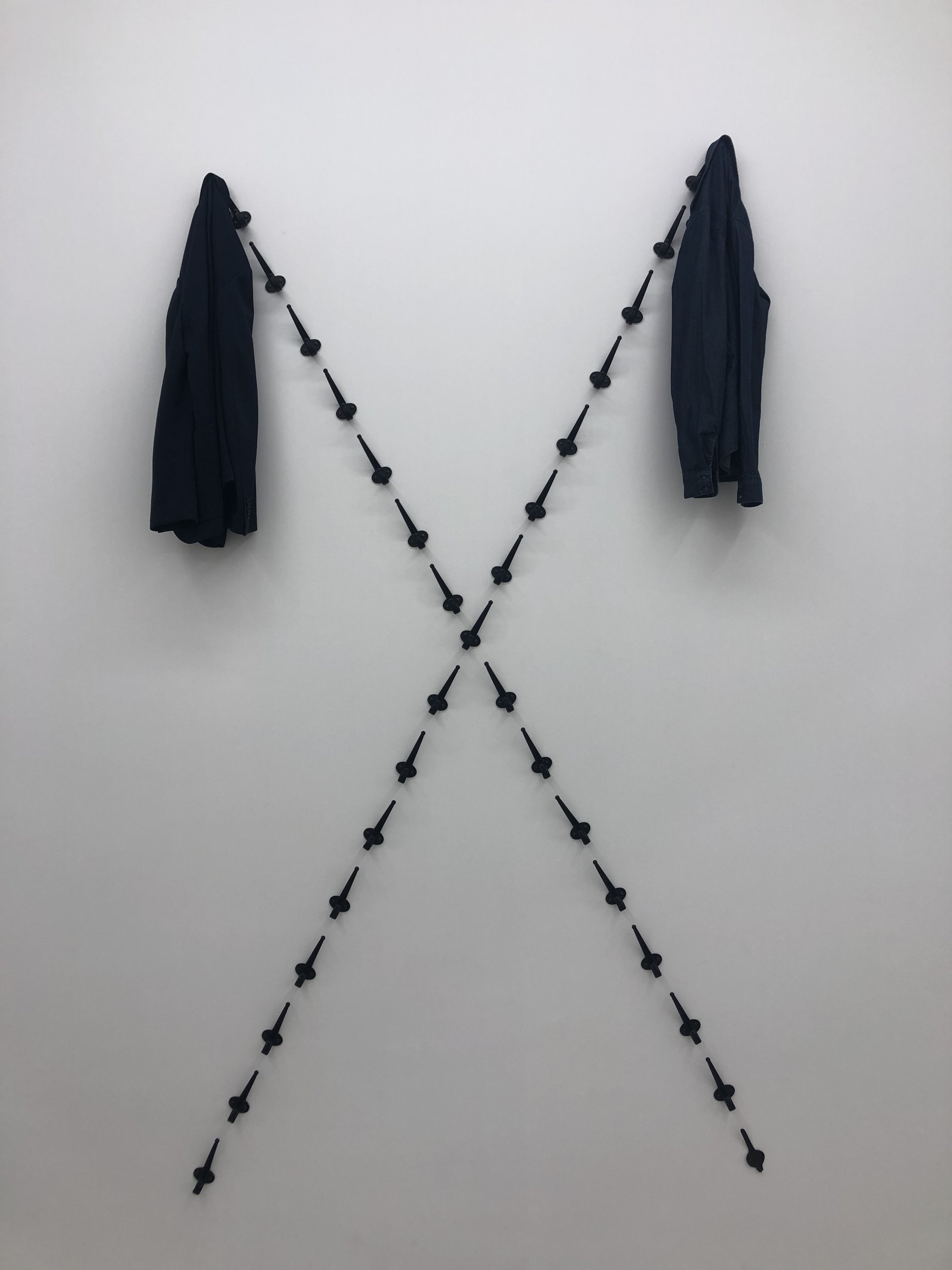 An installation comprising of two coats and coat hangers forming an “X” shape by Şakir Gökçebağ in 'Redimeyd' at Ferda Art Platform in Istanbul, Turkey. (Courtesy of Şakir Gökçebağ)