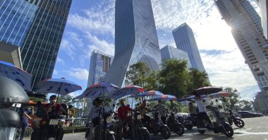 Men on electric bikes wait for riders near the Evergrande headquarters (C) in Shenzhen, China, Sept. 24, 2021. (AP Photo)