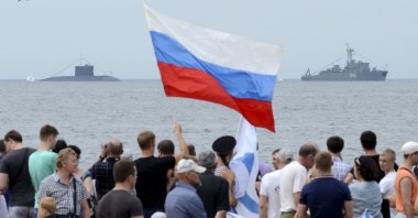 People gather to watch celebrations for Navy Day, with a Russian warship and a submarine seen in the background, in the far eastern city of Vladivostok, Russia, July 26, 2015. (Reuters Photo)