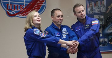 Crew members, cosmonaut Anton Shkaplerov (C), actress Yulia Peresild (L) and director Klim Shipenko, shake hands during a news conference ahead of the expedition to the International Space Station (ISS) at the Baikonur Cosmodrome, Kazakhstan, Oct. 4, 2021. (Roscosmos via AFP)