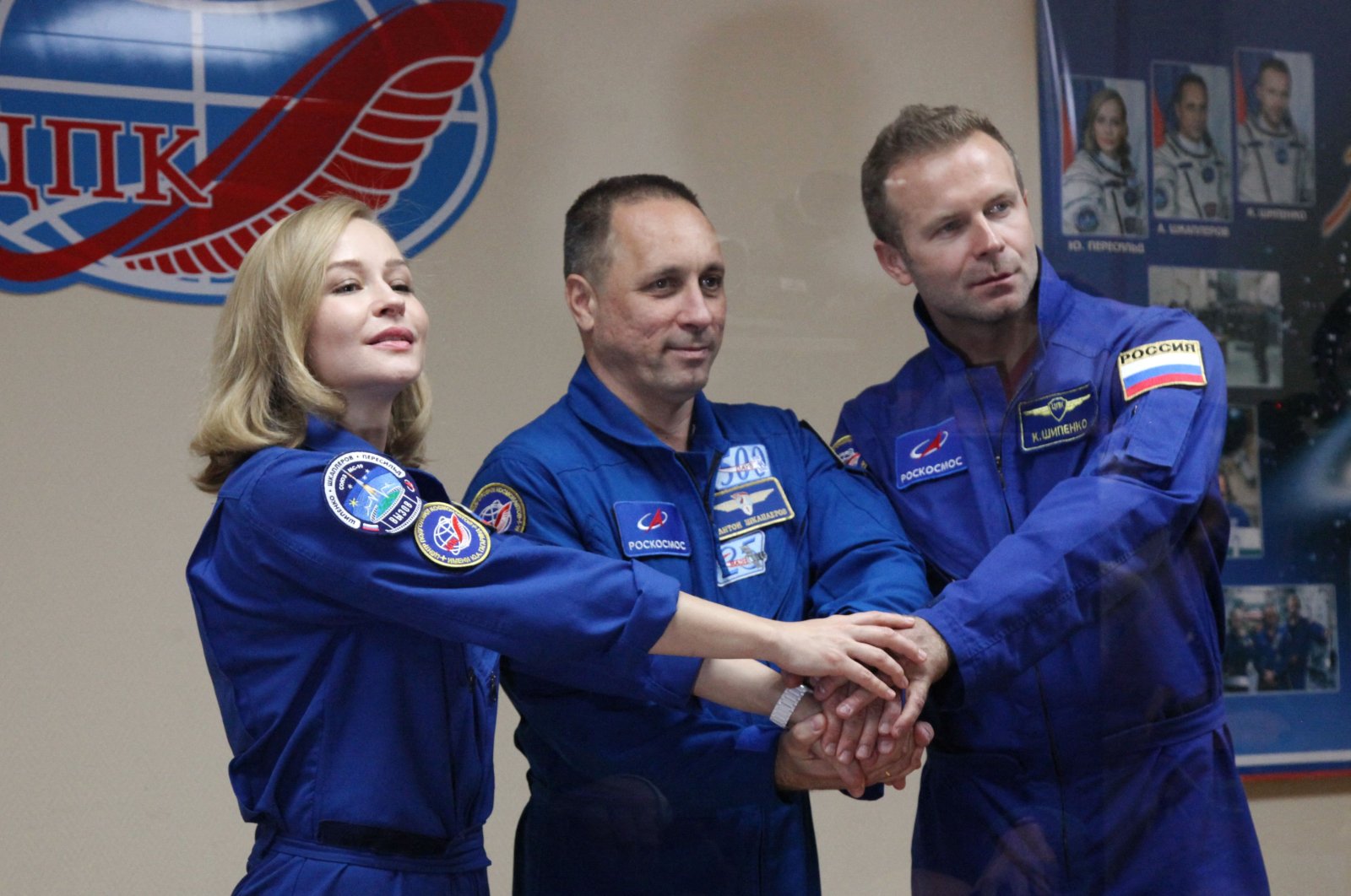 Crew members, cosmonaut Anton Shkaplerov (C), actress Yulia Peresild (L) and director Klim Shipenko, shake hands during a news conference ahead of the expedition to the International Space Station (ISS) at the Baikonur Cosmodrome, Kazakhstan, Oct. 4, 2021. (Roscosmos via AFP)