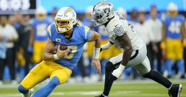 Los Angeles Chargers quarterback Justin Herbert runs with the ball as Las Vegas Raiders defensive end Yannick Ngakoue defends during the second half of an NFL football game, Inglewood, California, U.S., Oct. 4, 2021. (AP Photo)