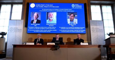 Goran K. Hansson (C), Secretary General of the Royal Swedish Academy of Sciences, and members of the Nobel Committee for Physics Thors Hans Hansson (L) and John Wettlaufer (R) sit in front of a screen displaying the co-winners of the 2021 Nobel Prize in Physics (L-R) Syukuro Manabe (U.S.-Japan), Klaus Hasselmann (Germany) and Giorgio Parisi (Italy) at the Royal Swedish Academy of Sciences in Stockholm, Sweden, Oct. 5, 2021. (AFP Photo)