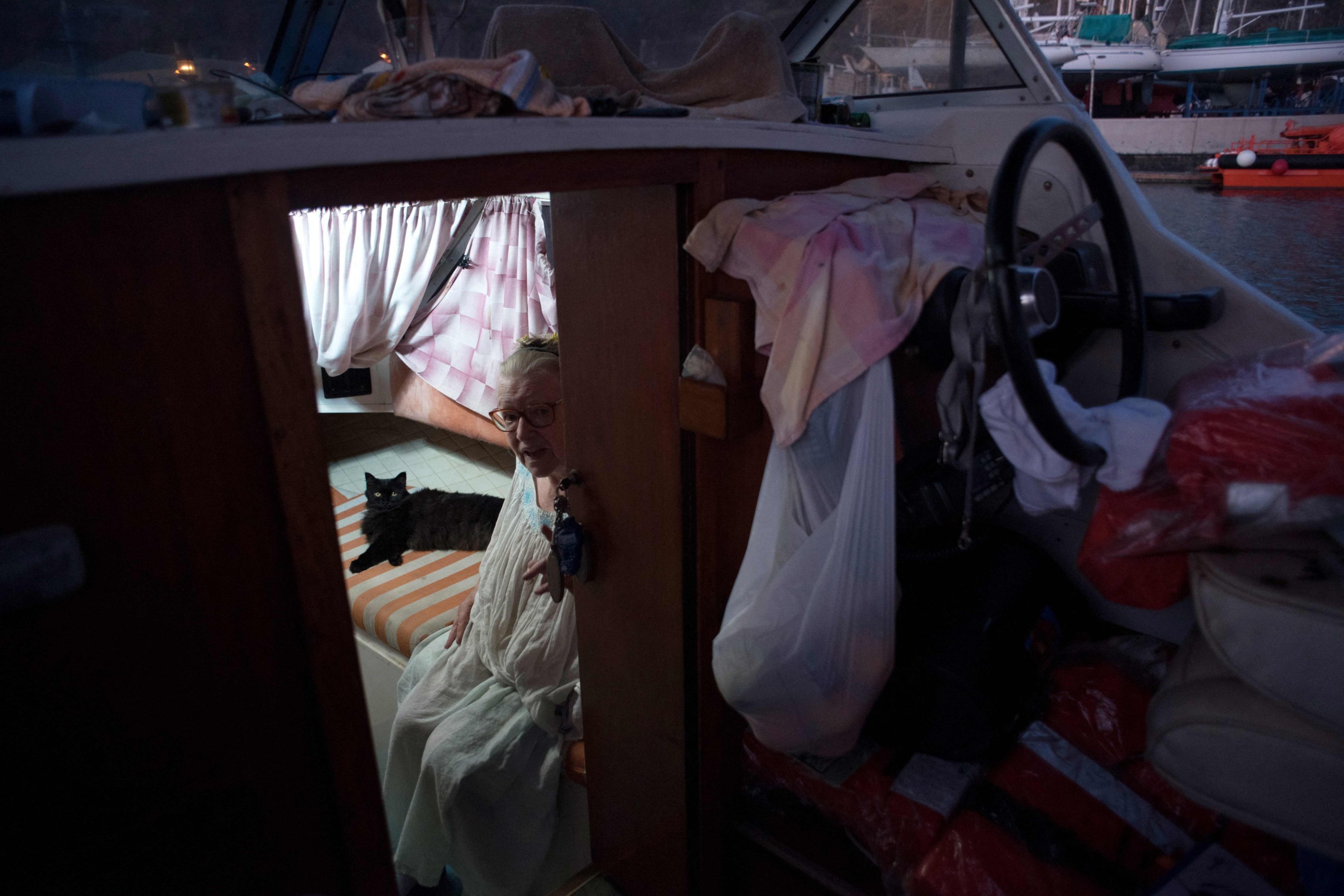 Margaretha, 80, sits next to her cat on the boat where she and her husband have settled after fleeing their home after the eruption of the Cumbre Vieja volcano, in the port of Tazacorte, on La Palma, Spain, Oct. 3, 2021. (AFP Photo)