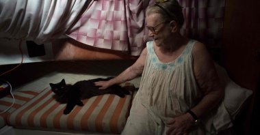Margaretha, 80, sits next to her cat on the boat where she and her husband have settled after fleeing their home after the eruption of the Cumbre Vieja volcano, in the port of Tazacorte, on La Palma, Spain, Oct. 3, 2021. (AFP Photo)