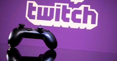 A console controller is pictured in front of a screen displaying the logo of Twitch in Toulouse, southwestern France, June 15, 2021 (AFP Photo)