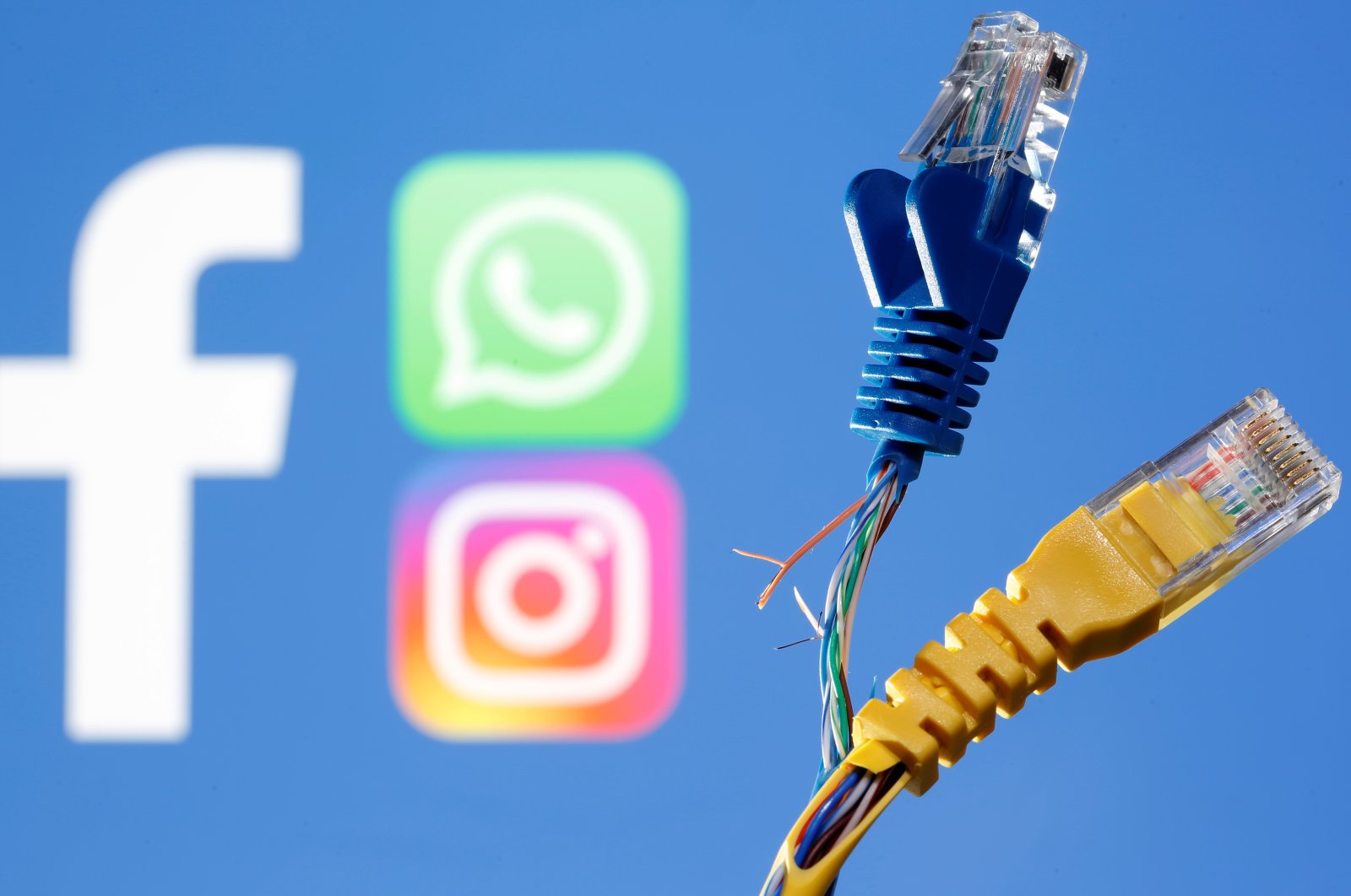 Broken ethernet cables are seen in front of the Facebook, WhatsApp and Instagram logos, Oct. 5, 2021. (Reuters Photo)