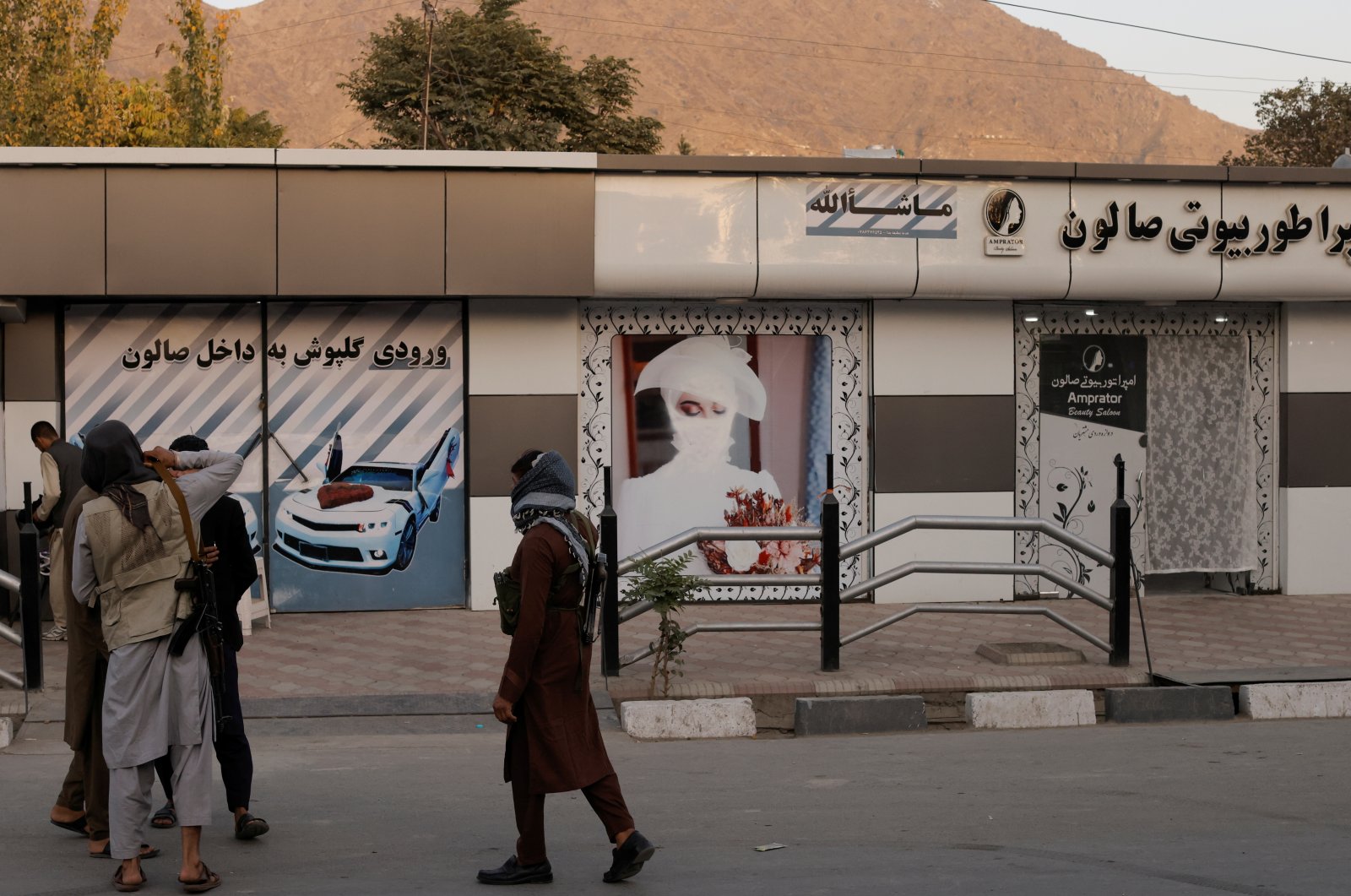 Armed Taliban men stand in front of a building with a defaced picture of a woman in Kabul, Afghanistan, Oct. 6, 2021. (Reuters File Photo)