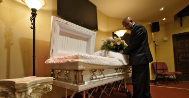 A funeral director arranges flowers on a casket before a service in Tampa, Florida, U.S., Sept. 2, 2021. (AP Photo)