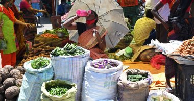 A vendor selling vegetables drinks water while waiting for customers at a weekend market in Chennai, India, Oct. 1, 2021. (AFP Photo)