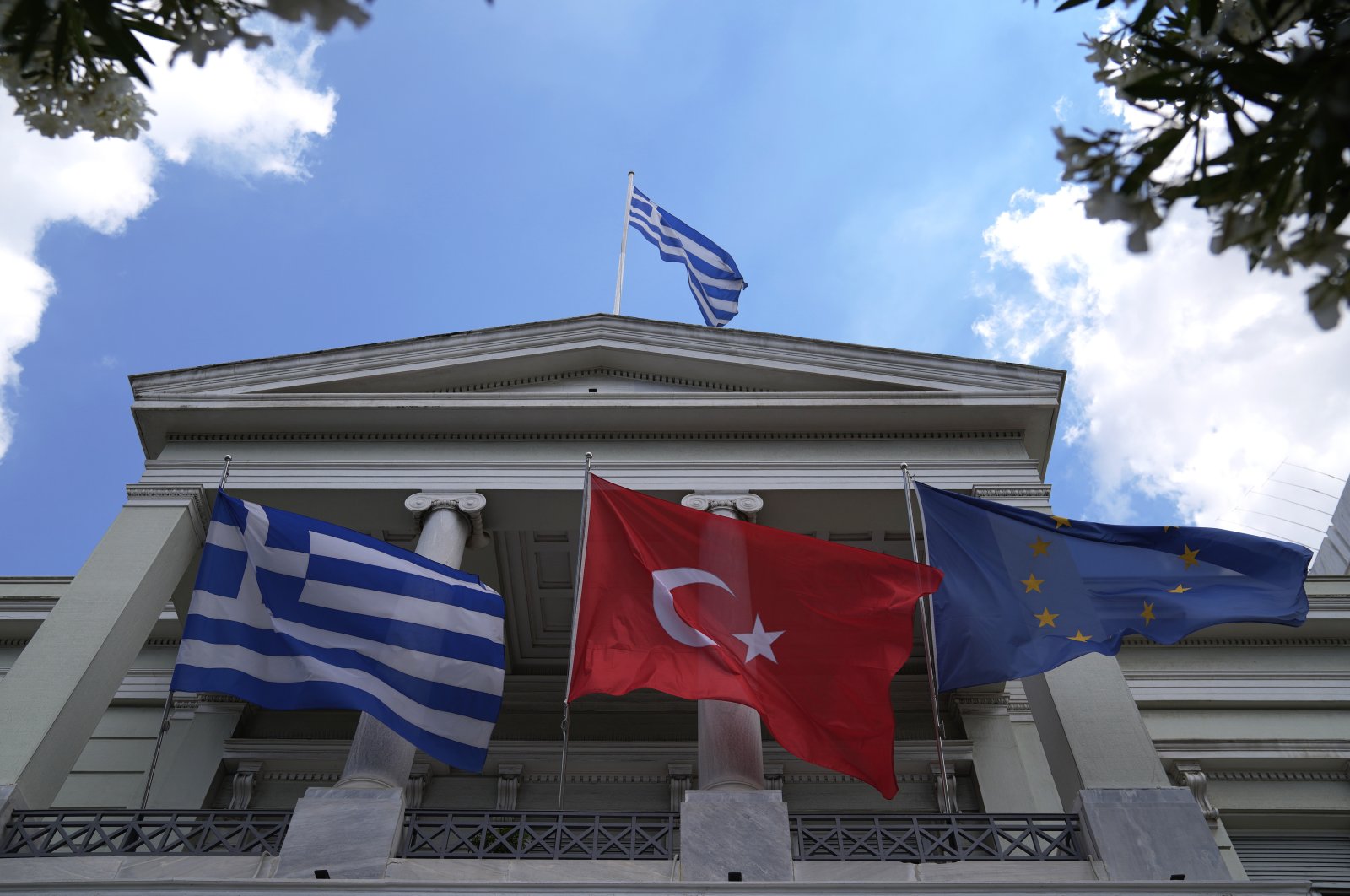 Turkish (C), Greek (L) and European Union flags wave on the Greek foreign ministry house, May 31, 2021. (AP File Photo)