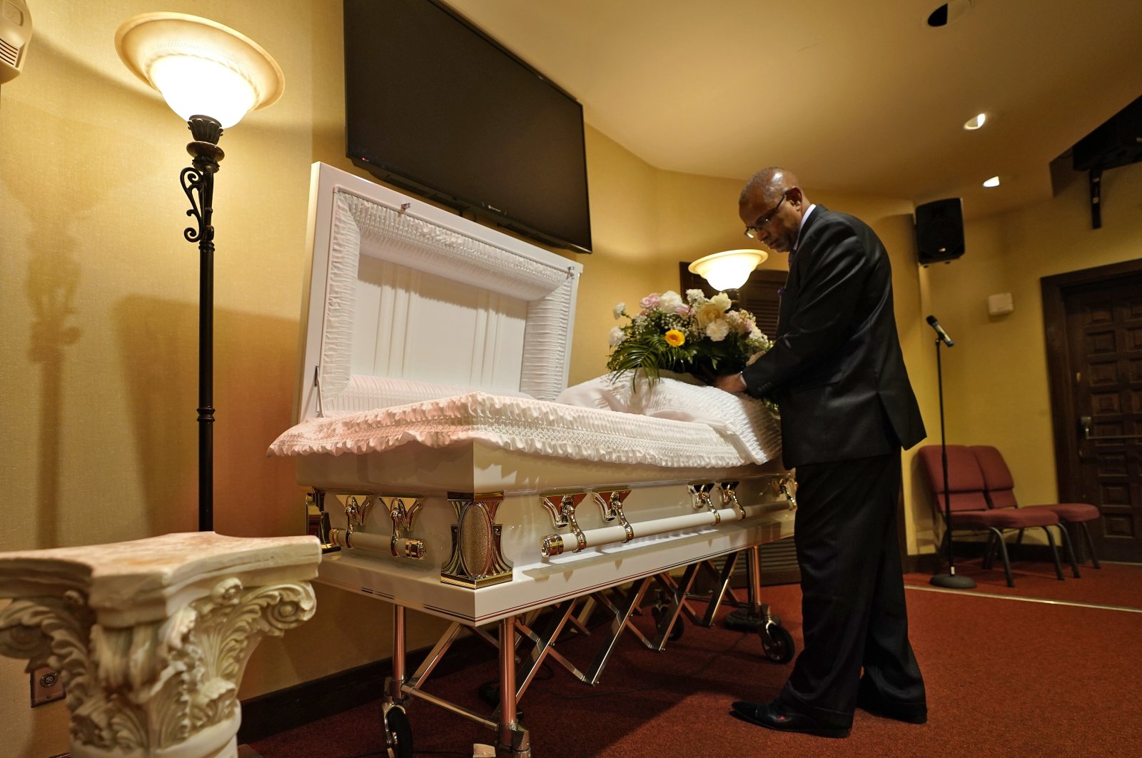 A funeral director arranges flowers on a casket before a service in Tampa, Florida, U.S., Sept. 2, 2021. (AP Photo)