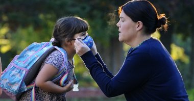Sarah Staffiere adjusts a face covering on her daughter, Natalie, before school, in Waterville, Maine, U.S., Oct. 7, 2021. (AP Photo)