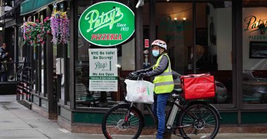 A restaurant delivery worker on his bike stops by a sign in the window of Patsy's Pizzeria which reads "NYC Be Safe! Be Strong!" during the coronavirus pandemic in New York City, U.S., April 23, 2020. (AFP Photo)