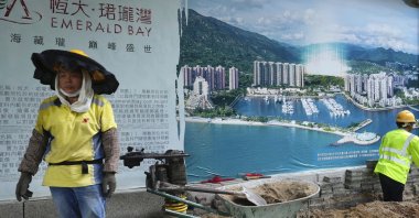 A worker walks past an advertisement photo of a China Evergrande Group property project outside its headquarters in Hong Kong, China, Oct. 4, 2021. (AP Photo)