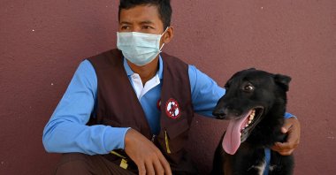 Trainer Khom Sokly sits with a dog trained to detect COVID-19 after a training session at the Cambodian Mine Action Centre (CMAC) in Kampong Chhnang province, Cambodia, Sept. 27, 2021. (AFP Photo)