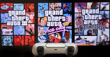 GTA: The Trilogy Definitive Edition - III, Vice City and San Andreas - on a TV screen with Playstation 5 game controller. (Shutterstock Photo) 