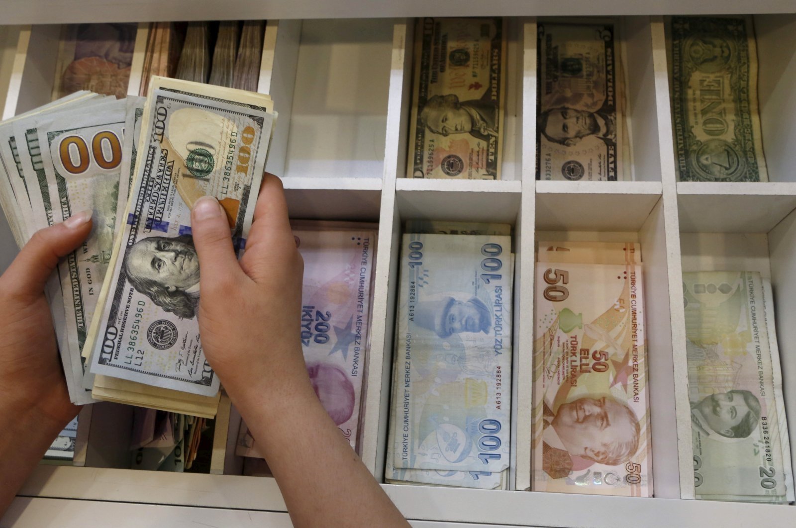 A money changer counts U.S. dollar bills, with Turkish lira banknotes in the background, at a currency exchange office in central Istanbul, Turkey, Aug. 21, 2015. (Reuters Photo)