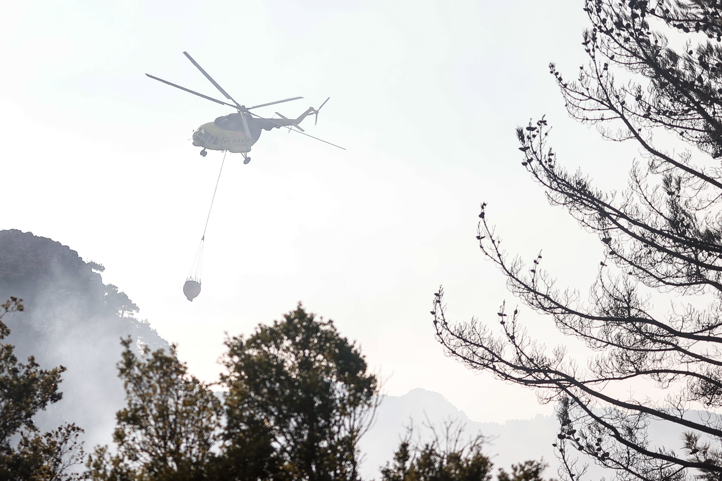 A helicopter participates in efforts to put out a wildfire in Kemer district of Antalya, Turkey, Oct. 13, 2021. (AA Photo)