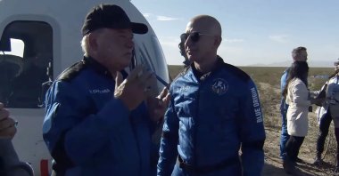 A handout screengrab released by Blue Origin shows Jeff Bezos (R) greeting Canadian actor William Shatner (L) as he emerges from the capsule after landing following the New Shepard's NS-18 mission to space near Van Horn, Texas, U.S., Oct. 13, 2021. (Blue Origin Handout/EPA)