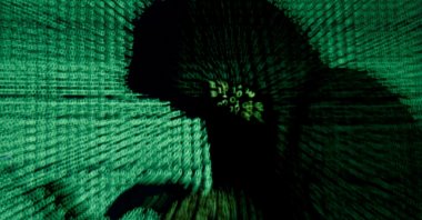 A man holds a laptop computer as cyber code is projected on him in this illustration picture taken on May 13, 2017. (Reuters Photo)