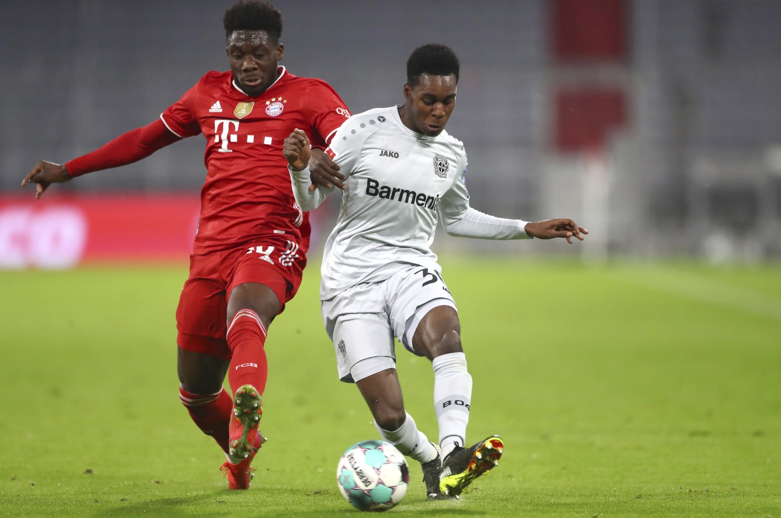 Bayern's Alphonso Davies (L) and Leverkusen's Jeremie Frimpong compete for the ball during a Bundesliga match at the Allianz Arena stadium in Munich, Germany, April 20, 2021. (AP Photo)