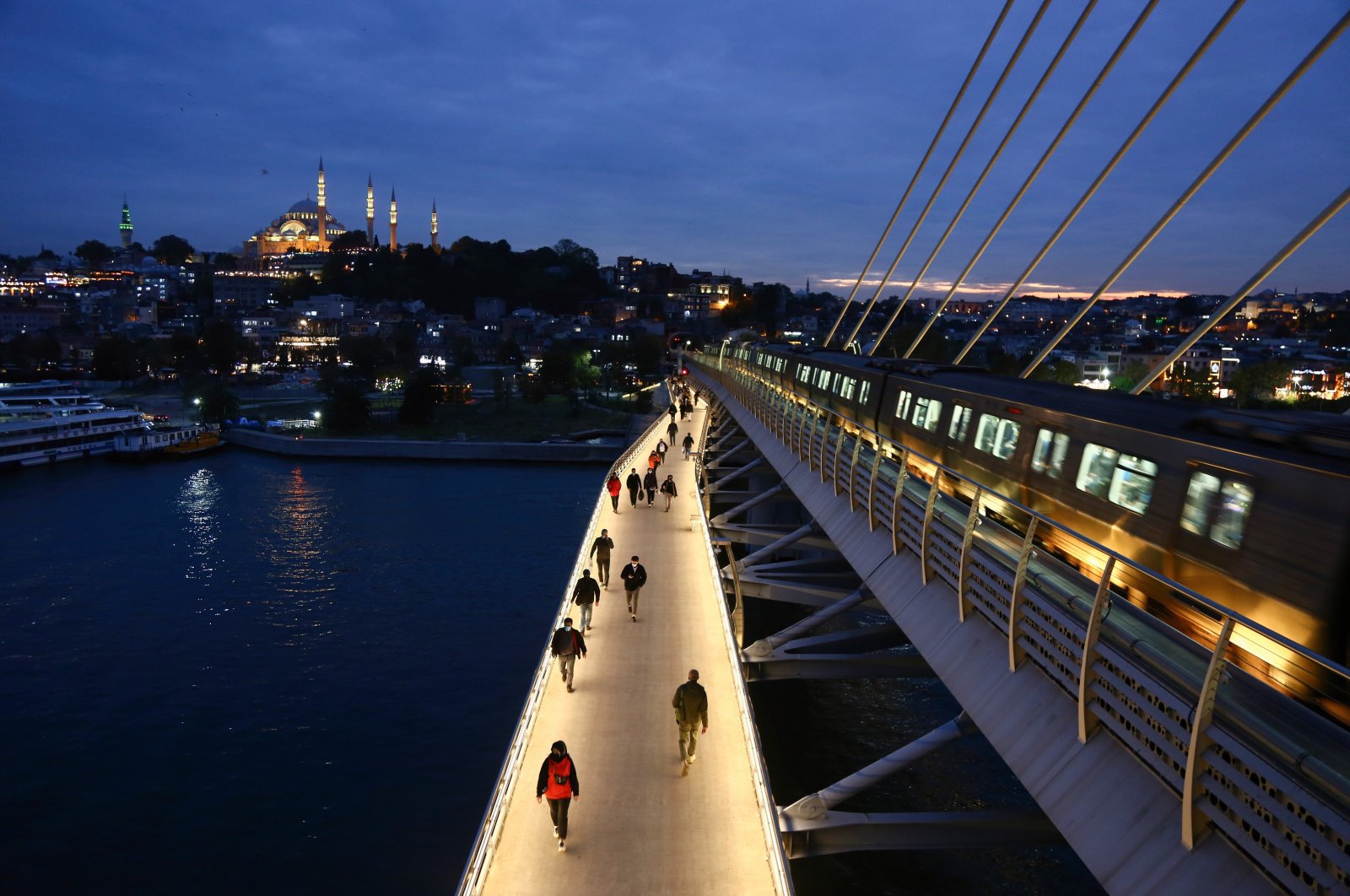 People are seen walking along the Golden Horn Metro bridge, with the Süleymaniye Mosque appearing in the background at sunset, Istanbul, Turkey, Oct. 3, 2021. (Photo by Getty Images)