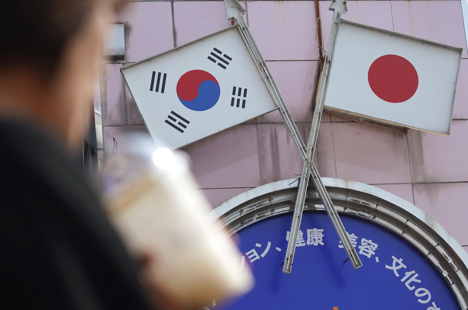 A woman walks past an advertisement featuring Japanese and South Korean flags at a shop in the Shin Okubo area in Tokyo, Japan, Aug. 2, 2019. (AP Photo)