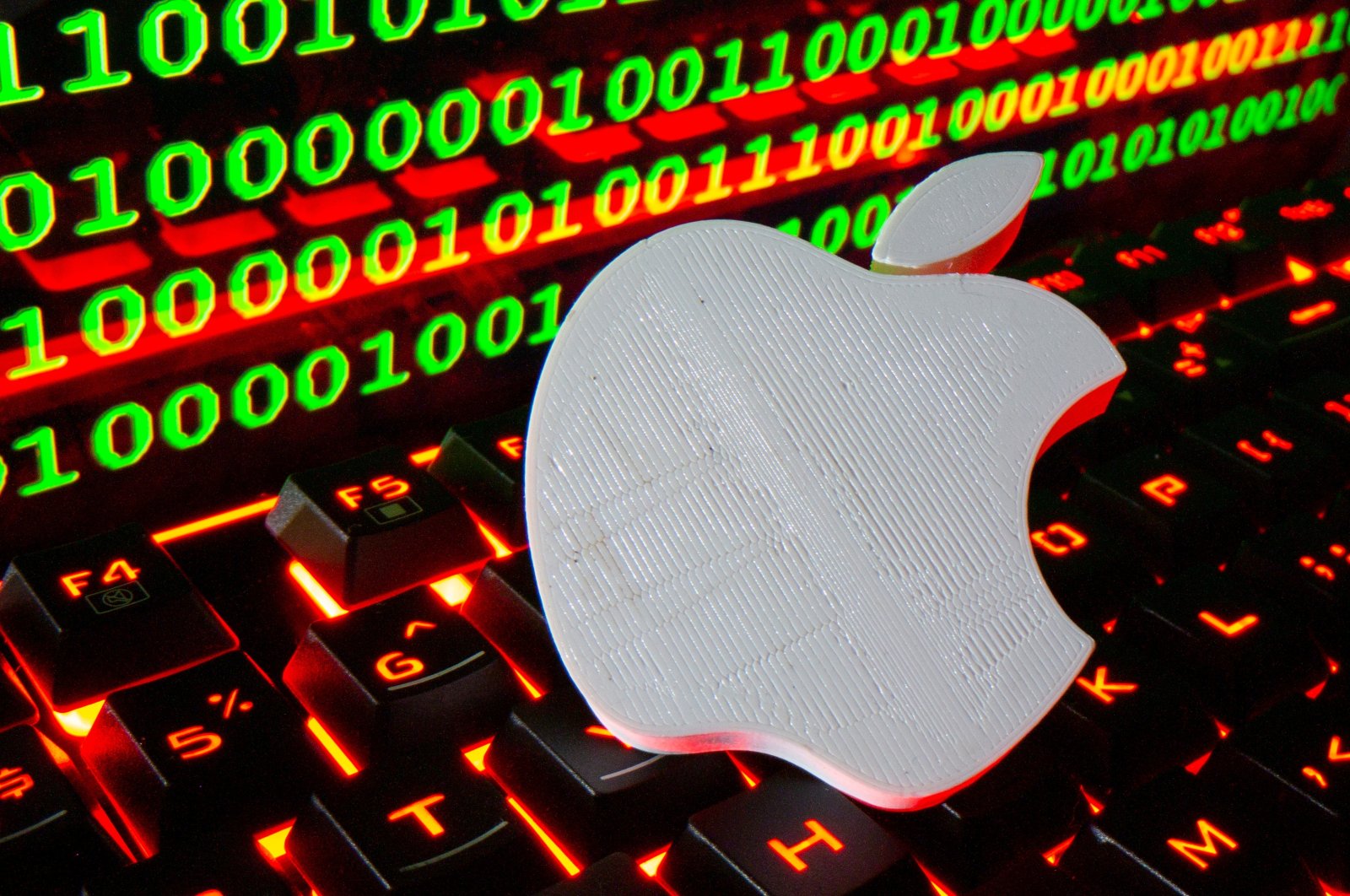 A 3D printed Apple logo is pictured on a keyboard in front of binary code in this illustration taken Sept. 24, 2021. (Reuters Photo)