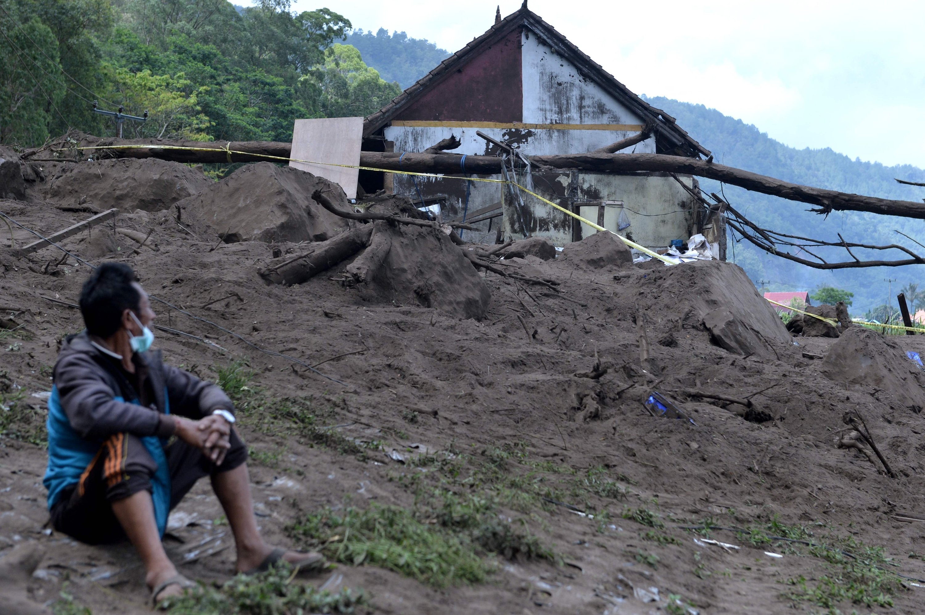 A resident sits near houses at the scene of a landslide triggered by a 4.8 magnitude earthquake at Trunyan village in Bangli, Indonesia