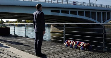 French President Emmanuel Macron stands at attention after laying a wreath near the Pont de Bezons during a ceremony commemorating the 60th anniversary of the massacre of Oct. 17, 1961, a murderous repression by the French police of a demonstration by Algerians in Paris during the violent decolonization process, in Colombes near Paris, France, Oct. 16, 2021. (Reuters Photo)
